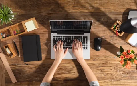 person-using-laptop-computer-close-up-office-wooden-desk-103349924